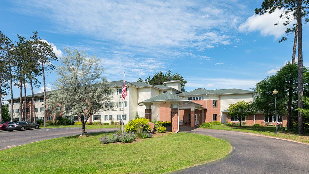 A picturesque building with a well-maintained landscape and a circular driveway under a clear blue sky.