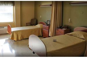 A hospital room with two beds and a curtain divider.