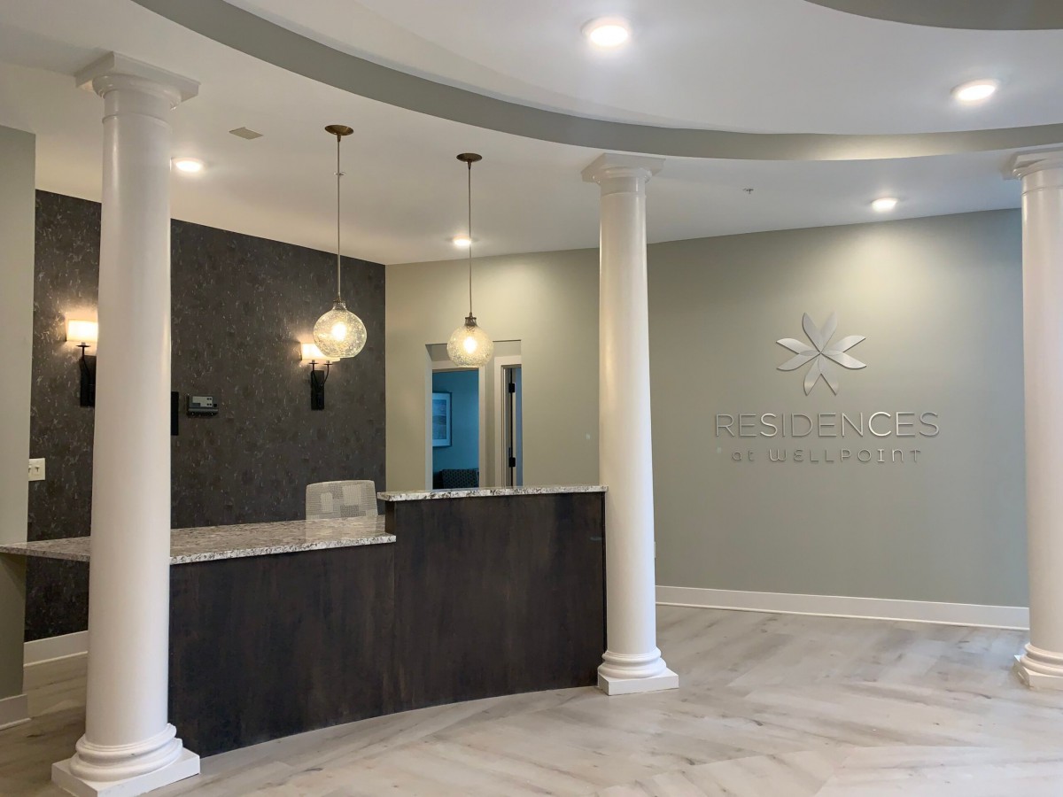A modern reception area with sleek design elements, featuring a curved desk, elegant lighting, and classic columns.