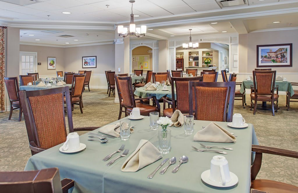 An elegant dining room with neatly arranged tables and chairs, featuring sophisticated place settings.