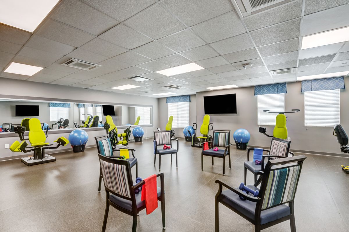 A spacious exercise room with chairs arranged in a circle, equipped with yoga mats and fitness balls.
