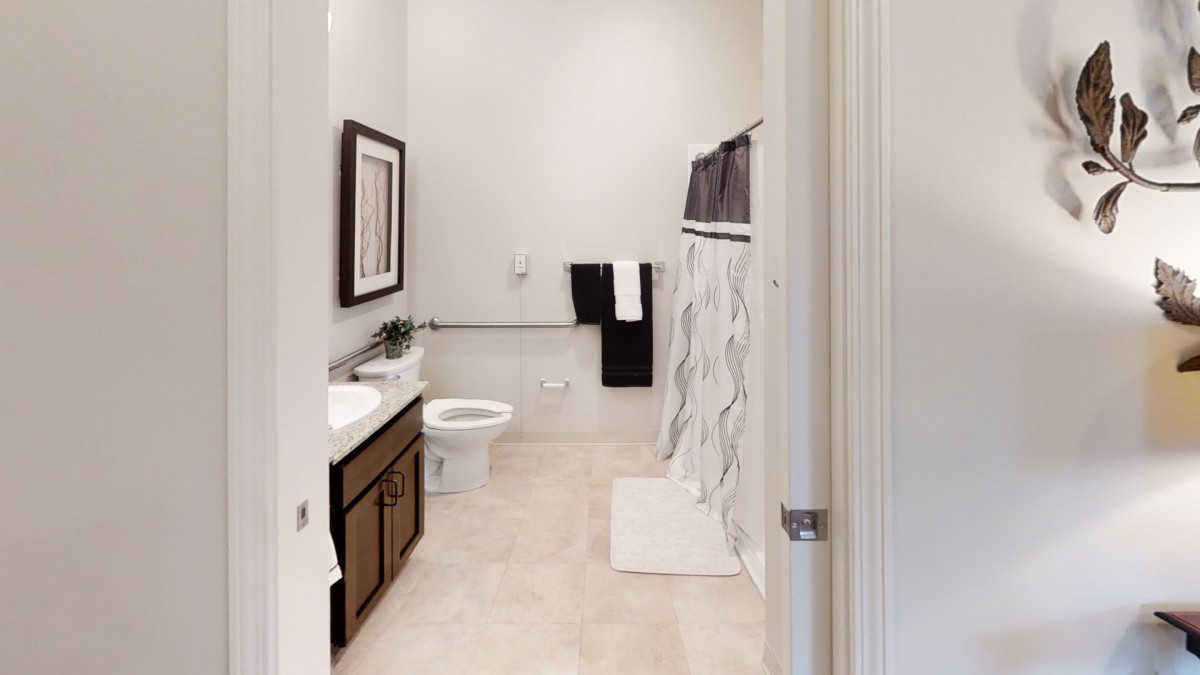 A modern bathroom with a shower curtain, toilet, and sink.