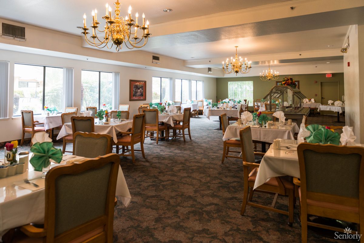 A spacious dining room with elegantly set tables and ornate chandeliers.