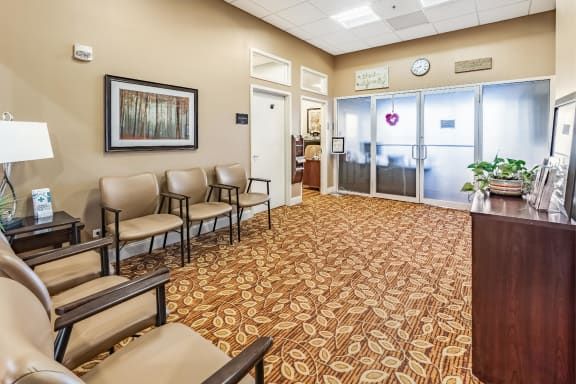 An empty waiting room with chairs, decorated carpet, and wall artwork.