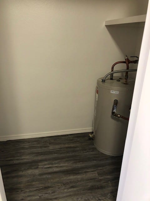 A utility room with a water heater installed against the wall.