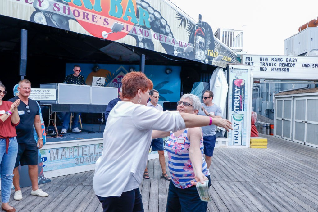 Two people joyfully dance together on a boardwalk.