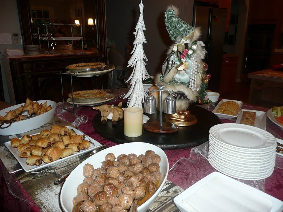 A festive dining table set for Christmas with a variety of foods and seasonal decorations.