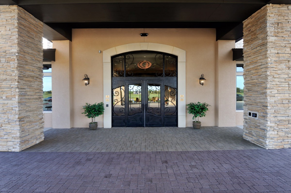 A symmetrical building entrance with double doors and potted plants on either side.