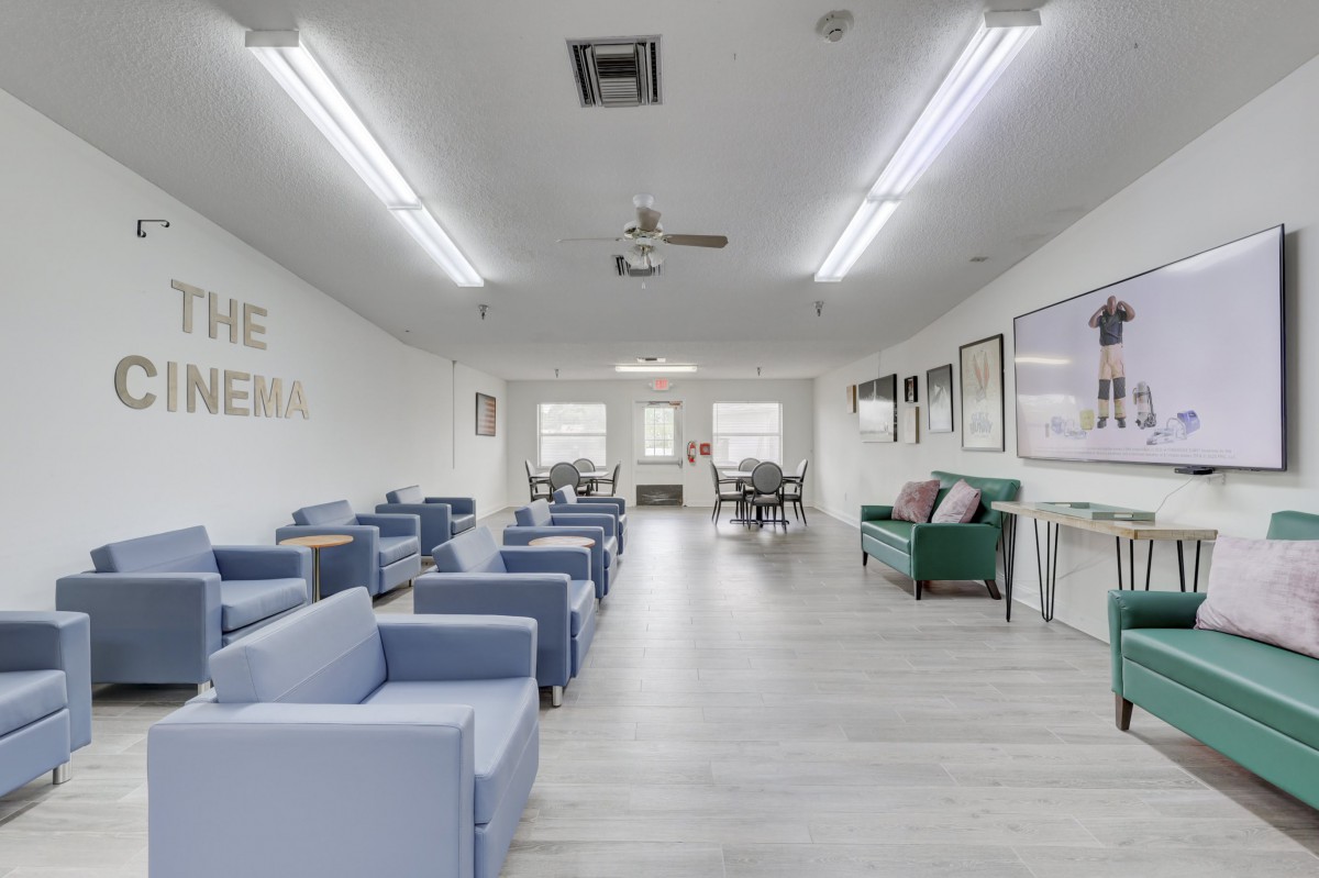 A modern waiting room with minimalist design, featuring blue chairs and ample lighting.