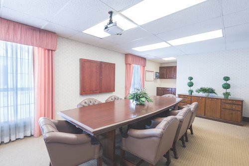 A well-lit conference room with a long meeting table and comfortable chairs.