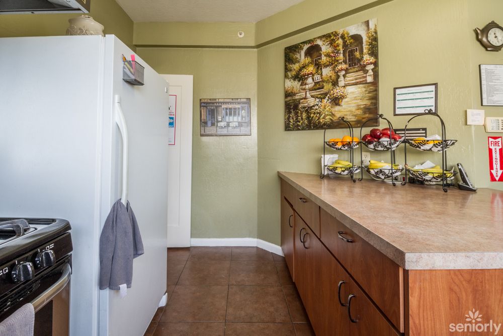 A cozy kitchen with a refrigerator, wooden cabinets, and decorative wall art.