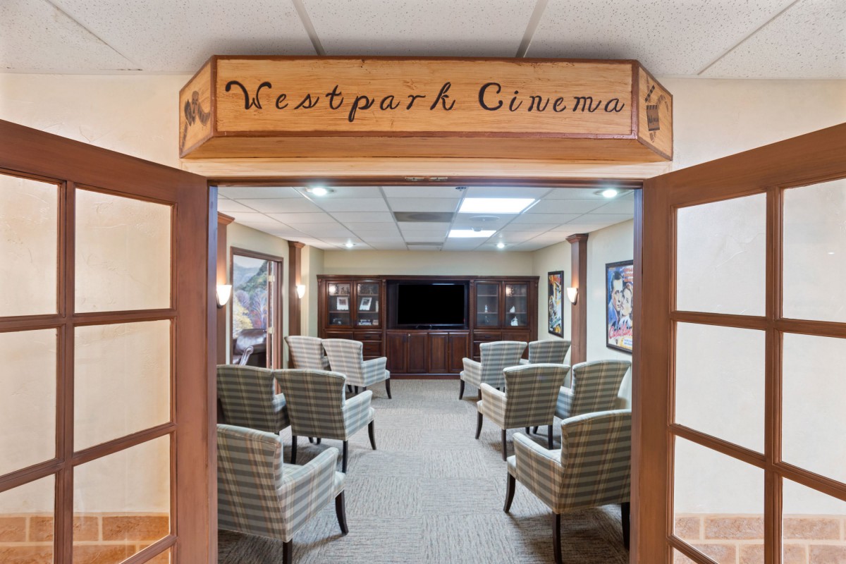 An inviting small cinema room with comfortable seating and a classic wooden sign reading 'Westpark Cinema'.