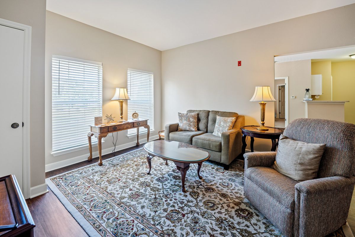 A cozy living room with comfortable seating, a patterned rug, and classic lamps.