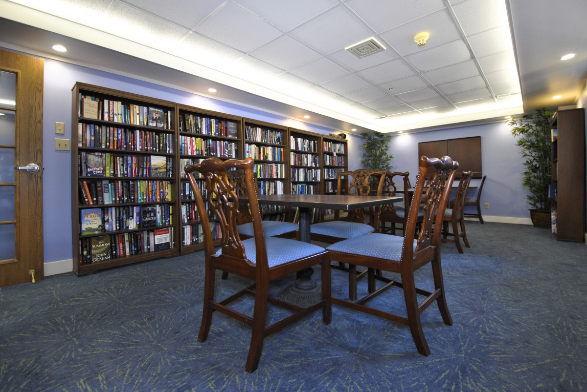 A quiet reading area in a library with wooden chairs and tables surrounded by bookshelves.
