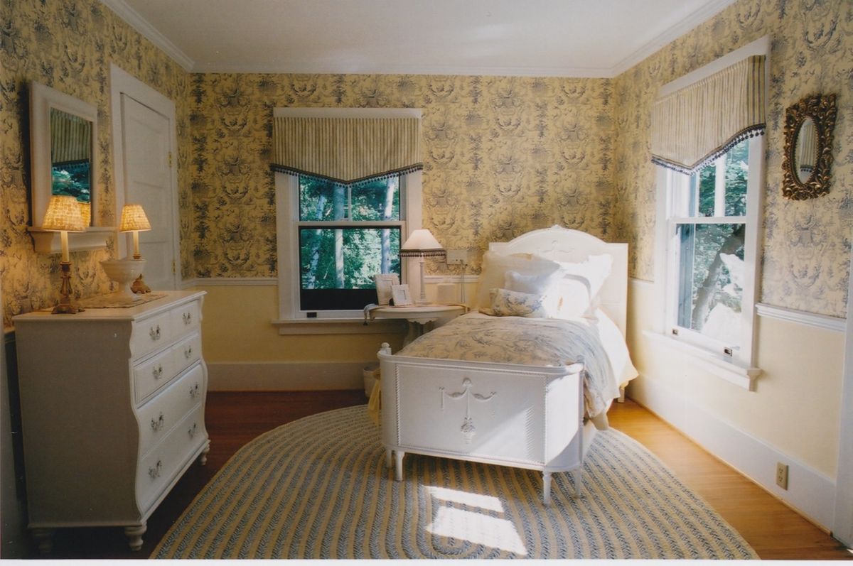 A cozy bedroom with vintage wallpaper and natural lighting.