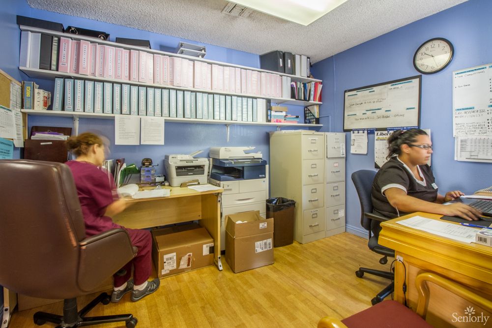 Two people working in an office with filing cabinets and office equipment.