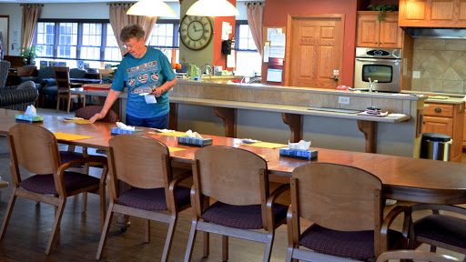 A woman prepares a dining area by setting the table.