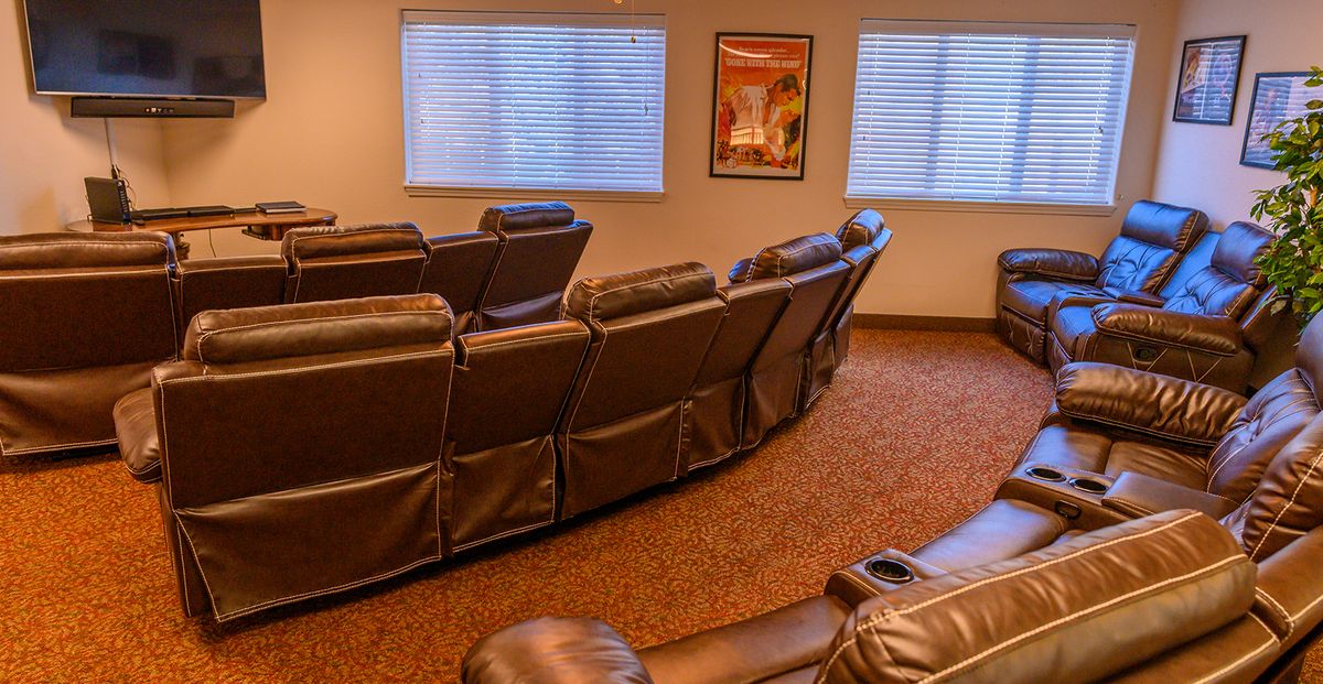 A cozy home theater with rows of comfortable recliner seats and movie posters on the wall.