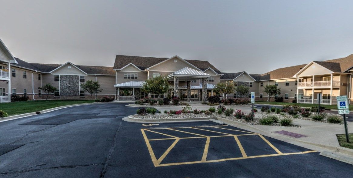 A modern building with a parking lot in front, surrounded by landscaped grounds.