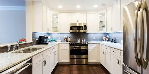 A modern kitchen featuring white cabinets, stainless steel appliances, and elegant wood flooring.