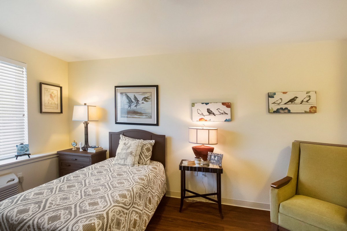 A cozy bedroom with a single bed, nightstand, and decorative wall art.
