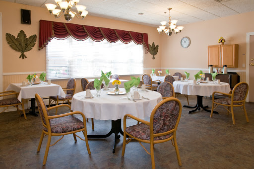 A cozy dining room set up with neatly arranged tables and chairs, illuminated by soft lighting.