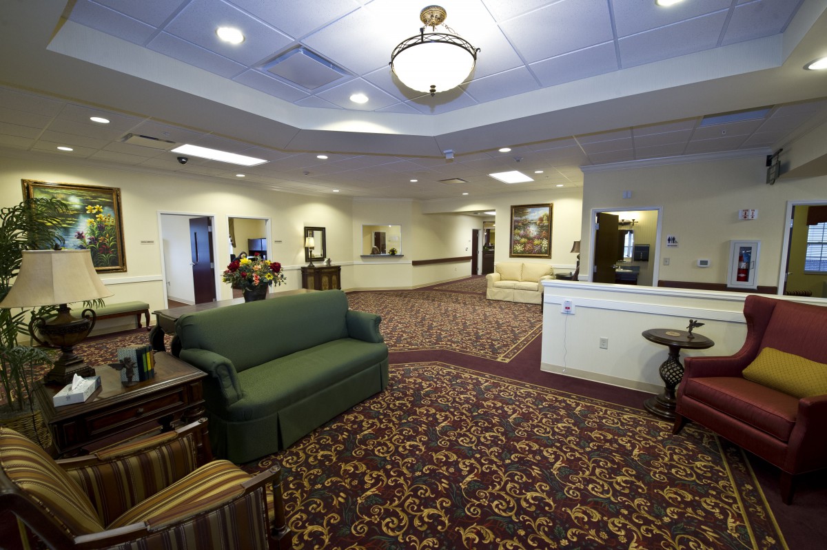A spacious lobby area with a green sofa, patterned carpet, and a reception desk.