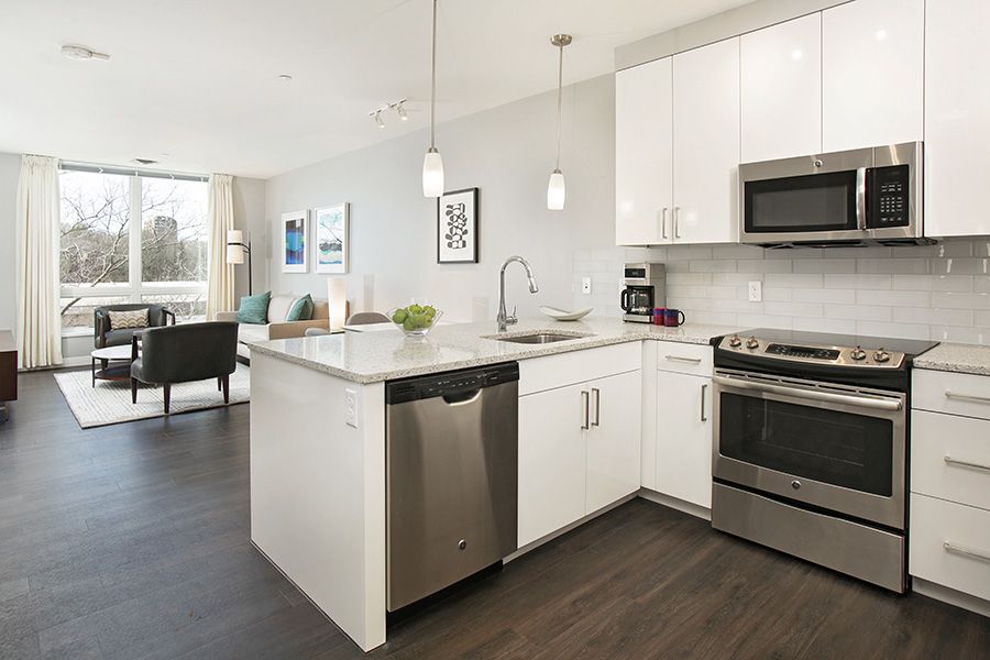 A modern kitchen with white cabinets and stainless steel appliances, featuring an island and open space design.