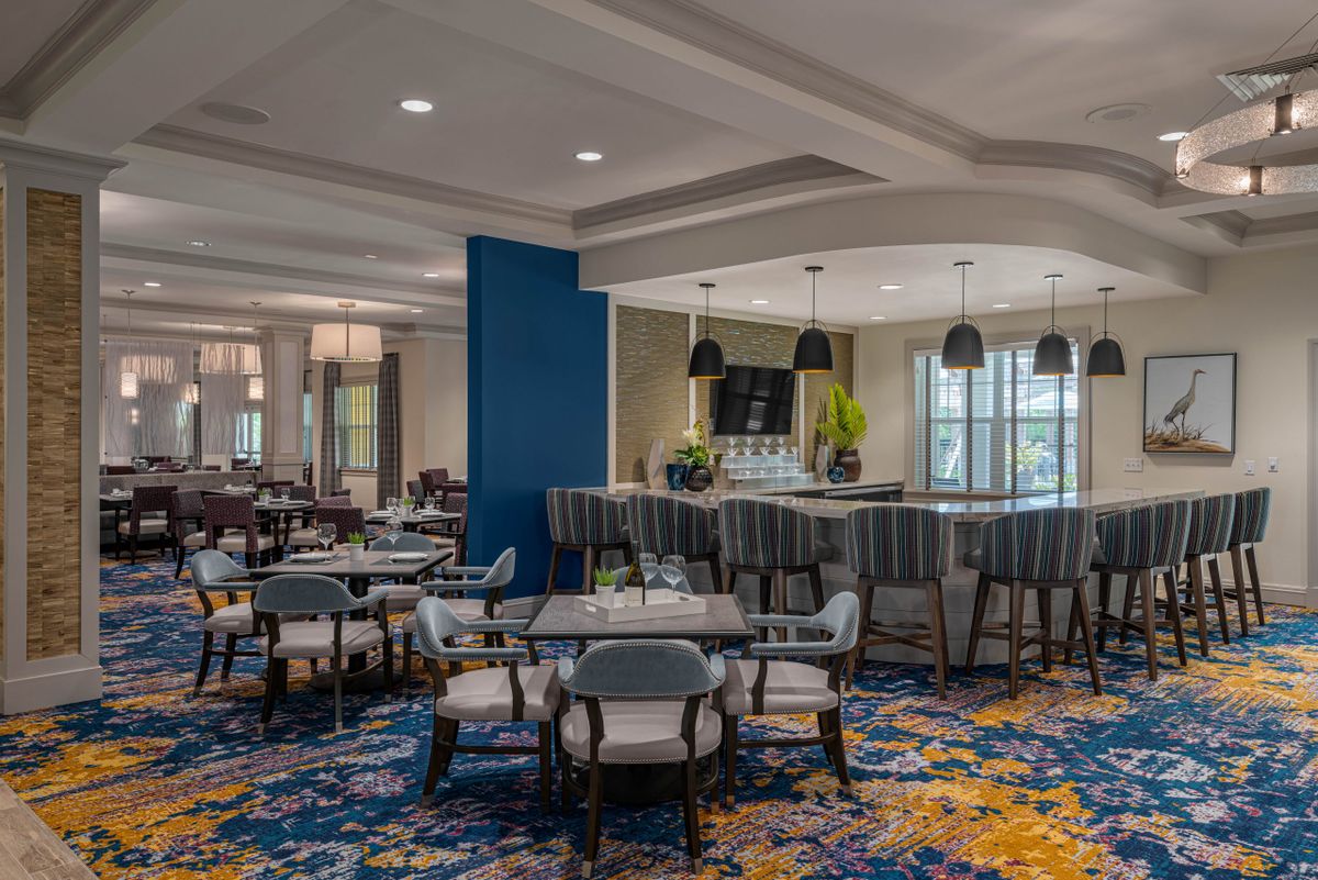 A modern restaurant interior featuring a dining area with stylish seating and a bar.