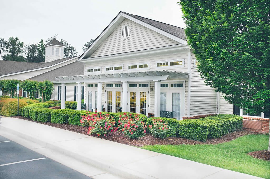 A well-maintained building with classic columns and surrounding landscaped gardens.
