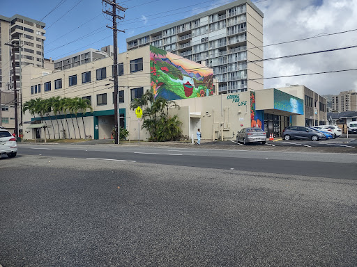 A vibrant mural adorns a building in an urban setting, showcasing public art amidst everyday street life.