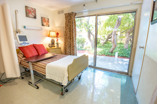 A well-lit hospital room featuring a comfortable bed and a view of the garden, designed for patient comfort and care.