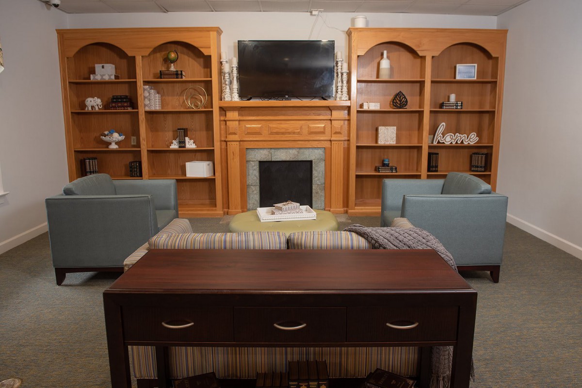 A cozy living room with a fireplace, wooden bookshelves, and comfortable seating.