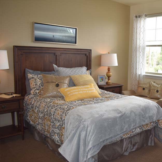 A cozy bedroom with a well-decorated bed, two lamps, and a window letting in natural light.