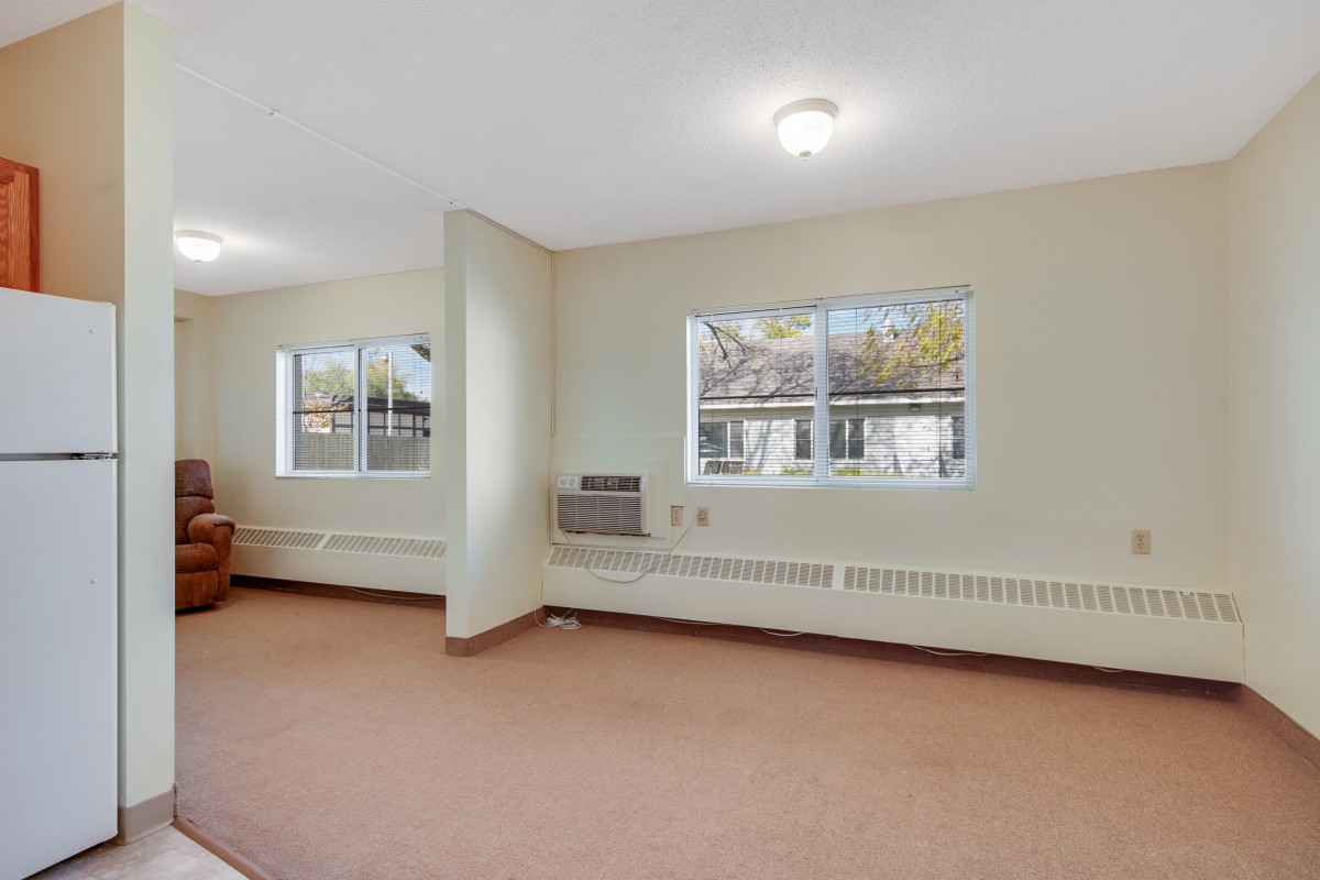An empty room with carpet flooring and windows allowing natural light.