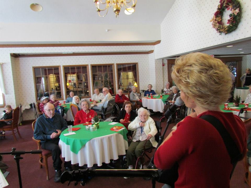 A group of people gathered indoors, listening to a speaker at an event.