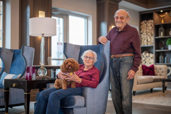 An elderly couple relaxing in their living room with their dog.