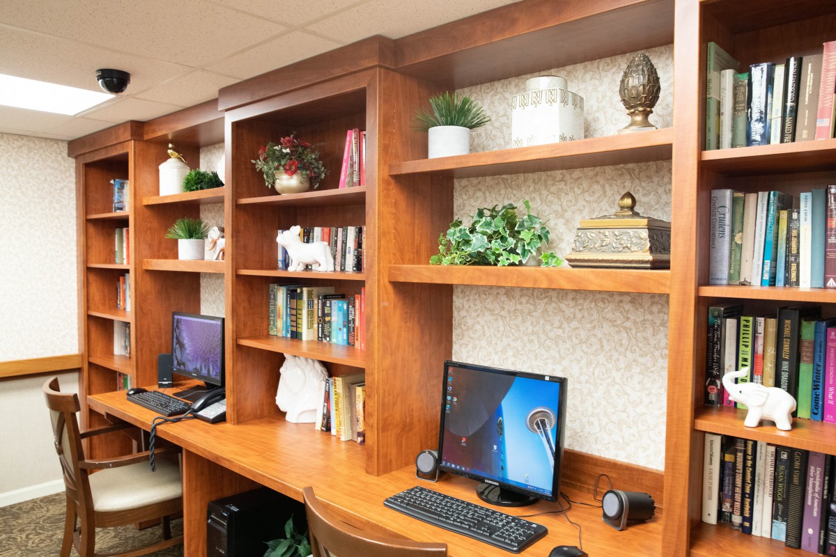 A well-organized office space with wooden shelves, a computer setup, and decorative plants.