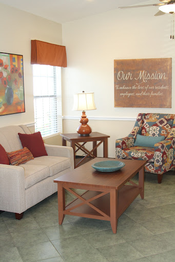 A cozy living room featuring a comfortable sofa and a colorful armchair, complemented by decorative artwork and a warm ambiance.