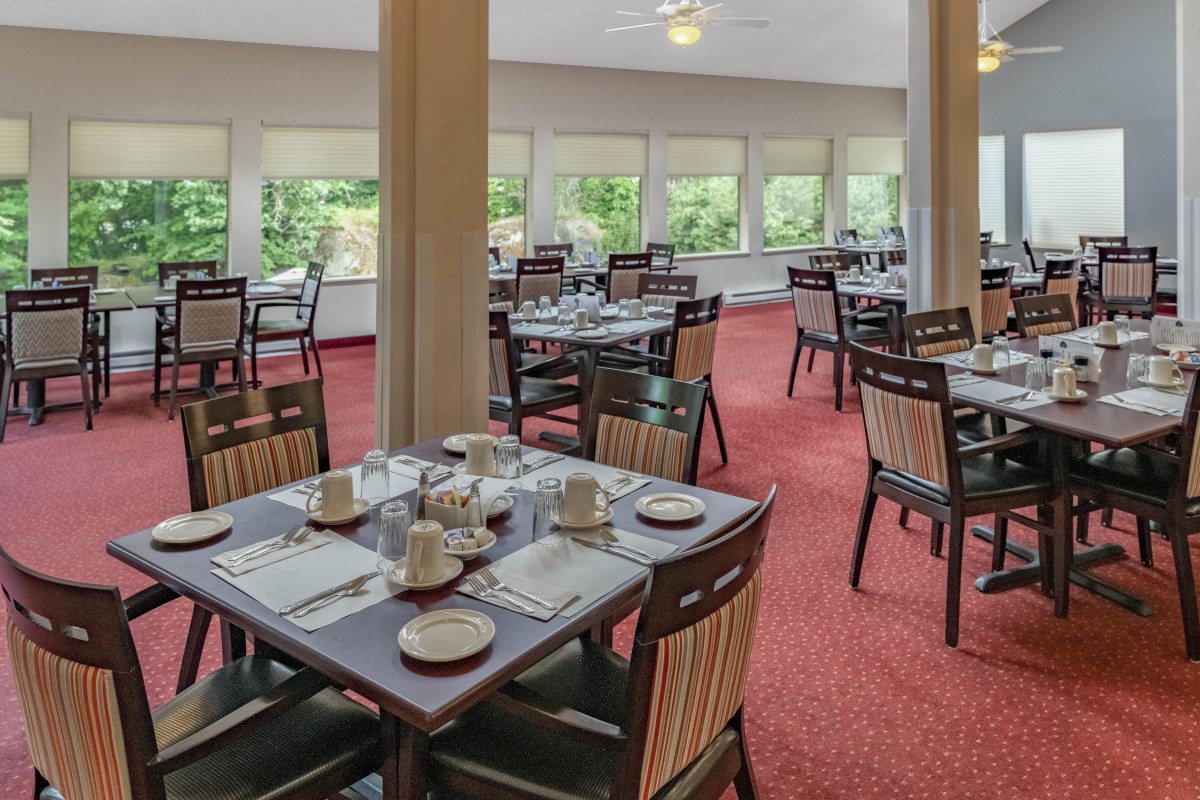 A spacious dining area with neatly arranged tables and chairs, surrounded by large windows.
