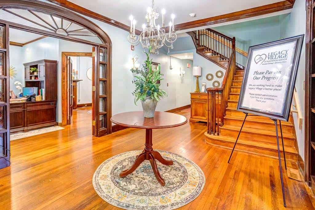 A beautifully decorated foyer with a central table, chandelier, and staircase.