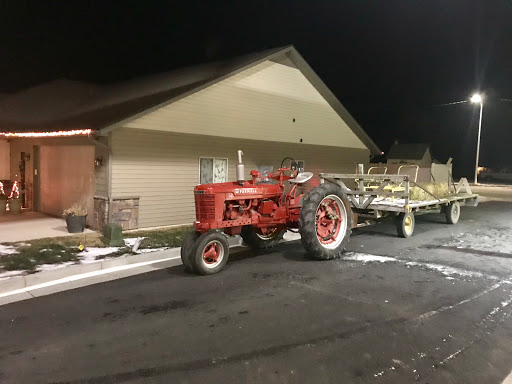 A red tractor parked next to a building at night.