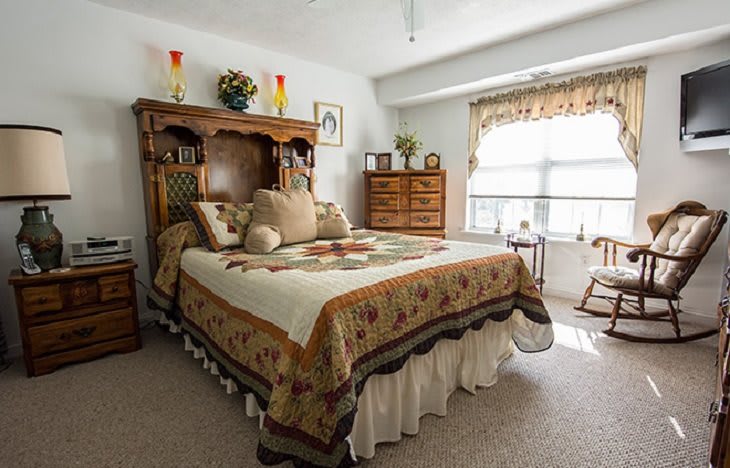 A cozy, traditional bedroom with a quilted bedspread and decorative pillows.