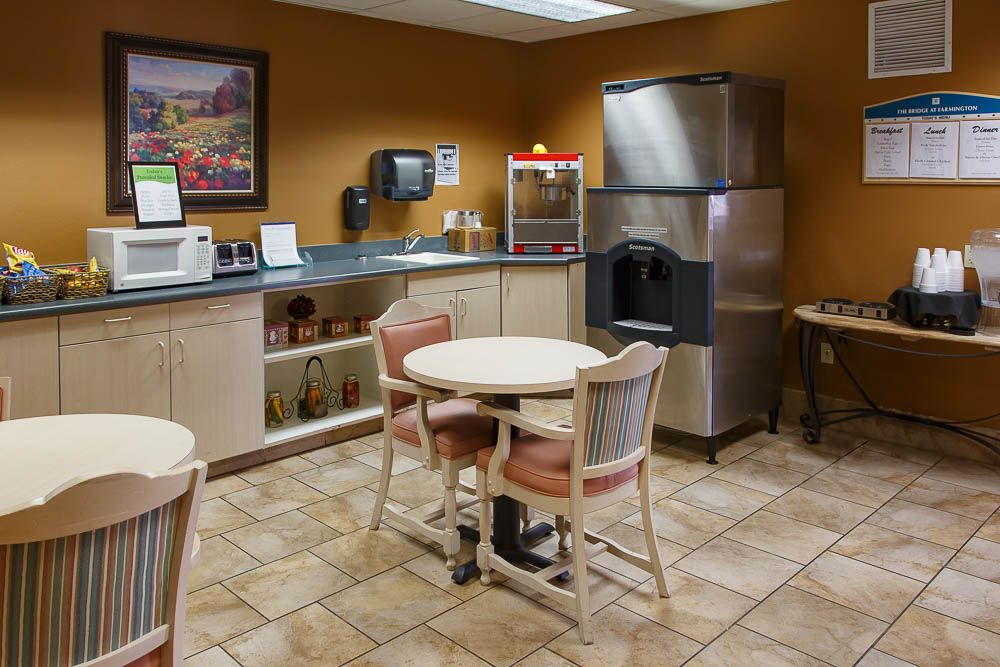 A small kitchen area with tables, chairs, and various appliances including a microwave and a popcorn machine.