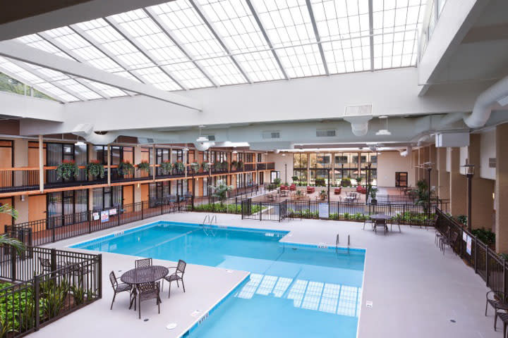 A spacious indoor pool area in a hotel, featuring comfortable seating and ample natural light.