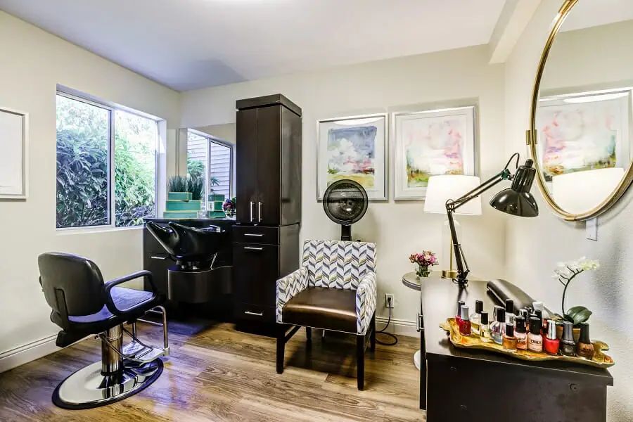 A cozy beauty salon equipped with a styling chair, dryer, and manicure station.