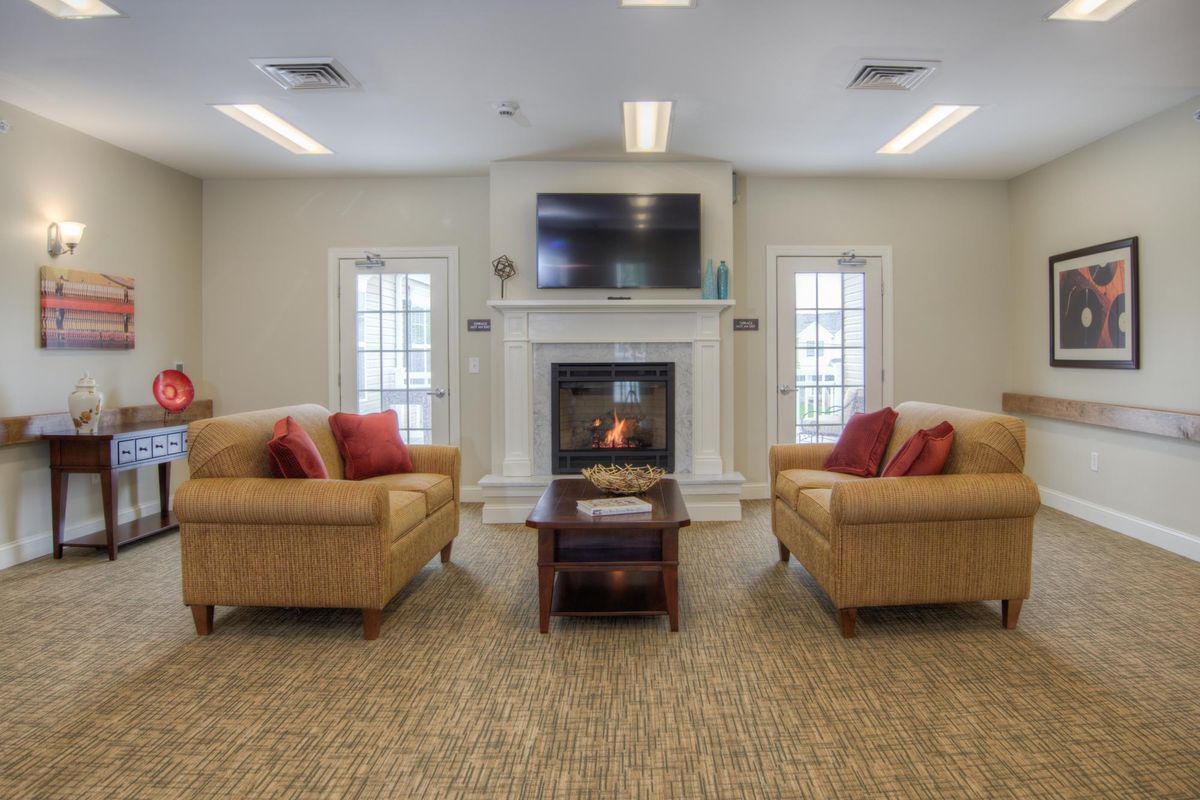 A cozy living room featuring a fireplace, two sofas with red pillows, and a wall-mounted television.