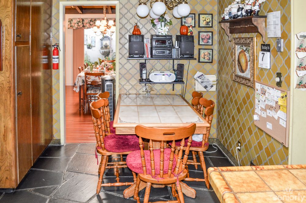 A cozy kitchen dining area featuring a wooden table and chairs, surrounded by vintage decor and wall art.