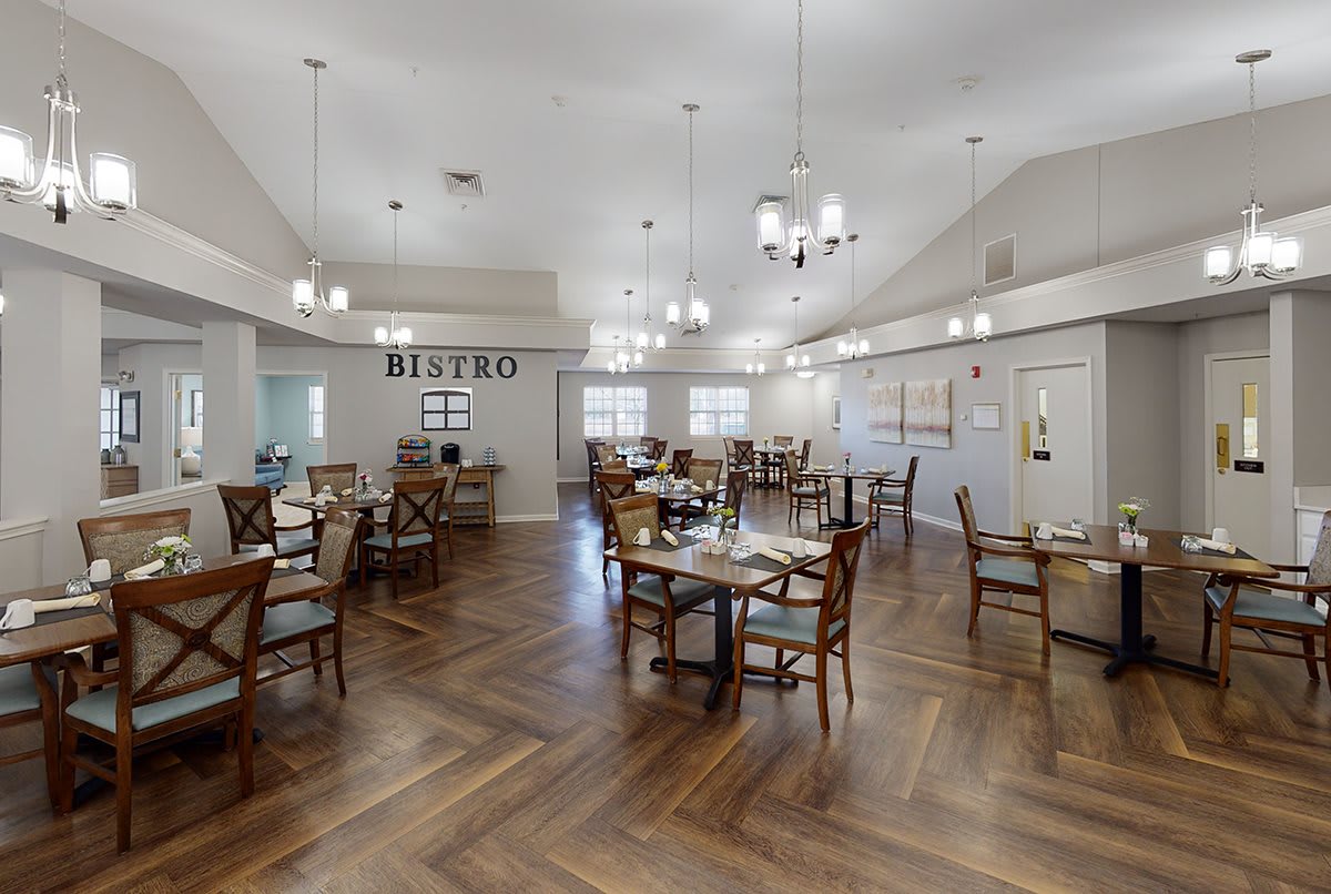 A modern and elegant dining area with empty tables and chandeliers.