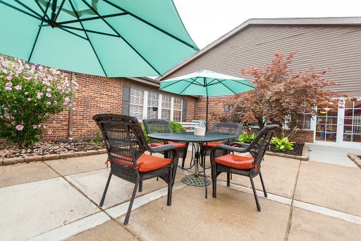 A cozy outdoor patio setup featuring a table and chairs with green umbrellas, perfect for enjoying a meal in the fresh air.